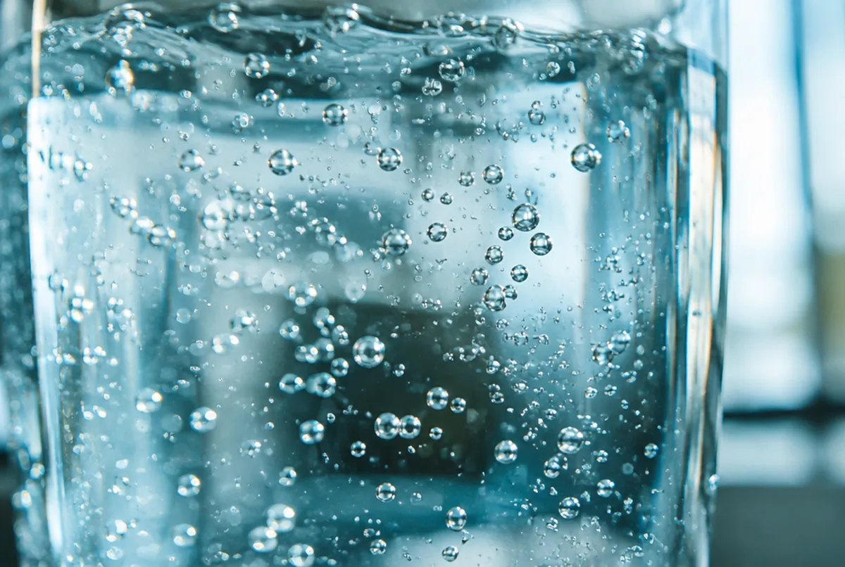 Winzige Gasbläschen steigen durch klares Wasser auf